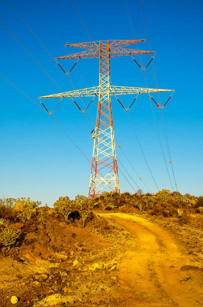 istock A tall power tower is standing in a field with a clear blue sky above it 2153708610