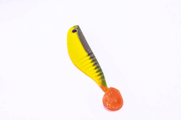 A yellow and green plastic fishing lure with a red tip. The image is of a close up of the lure
