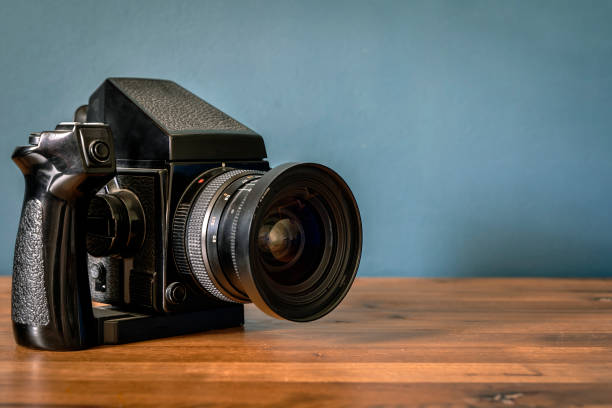 istock Camera is on the table. Medium format analog film camera on a blank background. Retro vintage technology style 2153710885
