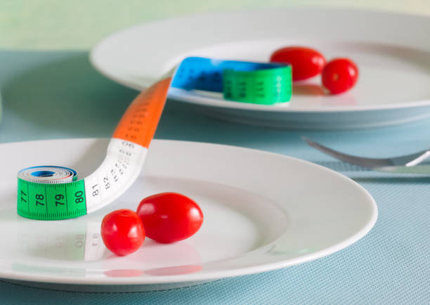 two plates with small tomatos and a tape measure, dieting,reducing weight, getting slim concept.Shallow depth of field.