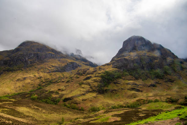 Picks of Sisters hidden in clouds, meadows in brown and yellow colours in a little bit of sun