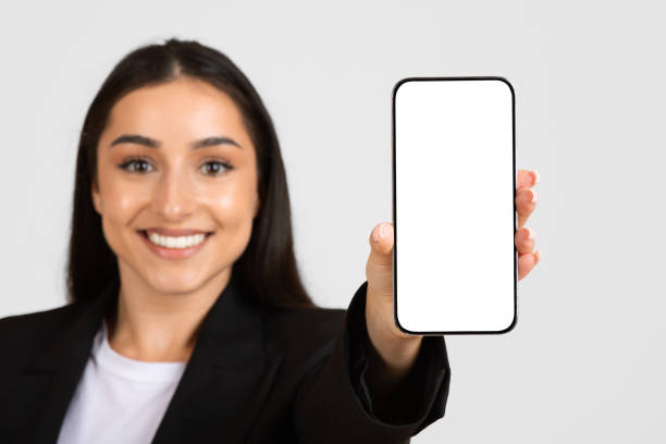 istock Happy business lady in suit, showing smartphone with empty screen, recommendation for work, study and business app 2153724744
