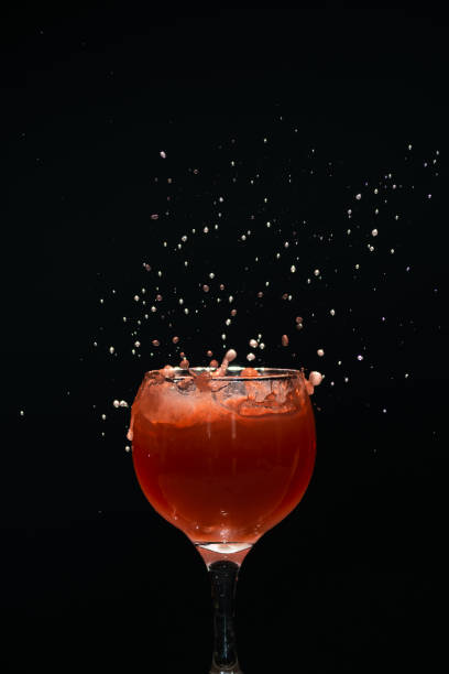 A glass cup with guava juice inside with splashes coming up.