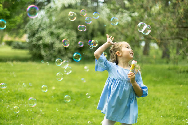 istock Young girl playing with bubbles in vibrant park setting. 2153730930