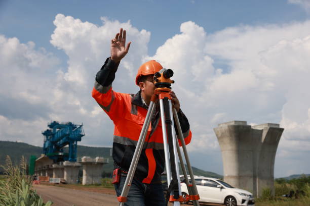 istock Construction engineer using a level survey for the construction foundation of the electric train rail system. Surveyor and survey equipment on construction site 2153736262