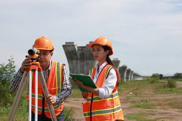 istock Construction engineer using a level survey for the construction foundation of the electric train rail system. Surveyor and survey equipment on construction site 2153736275