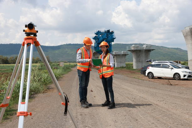 Construction engineer using a level survey for the construction foundation of the electric train rail system. Surveyor and survey equipment on construction site