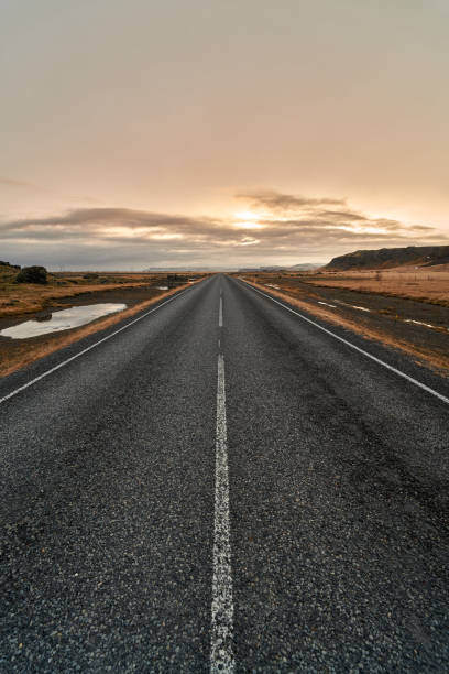 istock Straight endless road with sunset and clouds in the background 2153736352