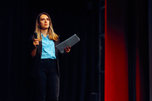istock Woman on a Stage Holding a Microphone Ready to Speak 2153745658