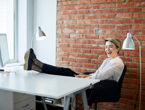 istock blond girl is laughing while sitting at the office table 2153747223