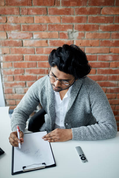 istock hardworking guy writing something on the paper 2153747226