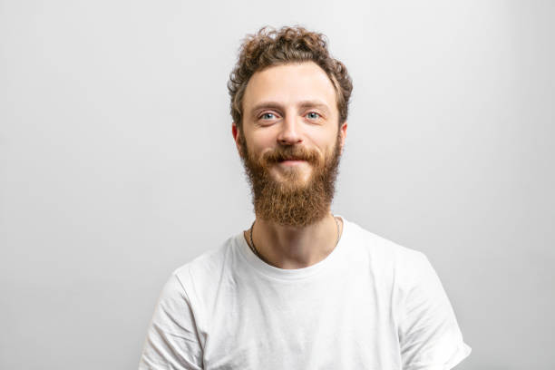 Handsome hipster man with beard smiling at camera over white background. Portrait of young handsome softie, good-looking kind hipster man with beard smiling and looking at camera over white background. man 30 years old stock pictures, royalty-free photos & images