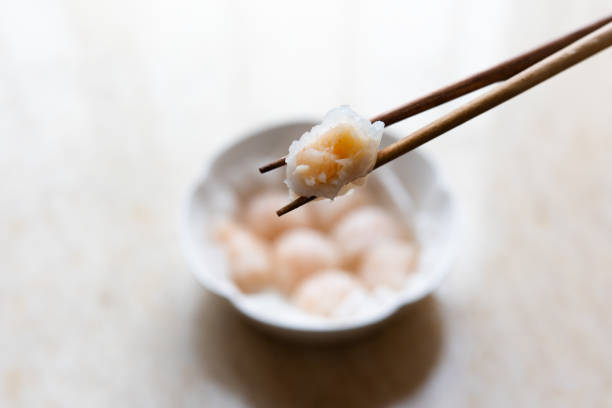 Dim sum for Chinese breakfast tea includes steamed shrimp dumplings served on a round plate with oiled paper.