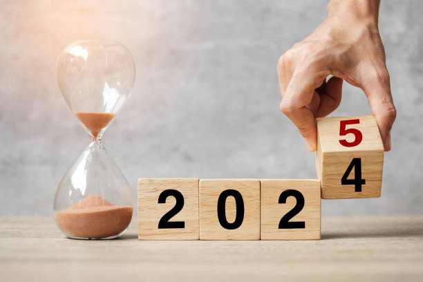 istock hand flipping block 2024 to 2025 text with hourglass on table. Resolution, time, plan, goal, motivation, reboot, countdown  and New Year holiday concepts 2153754087