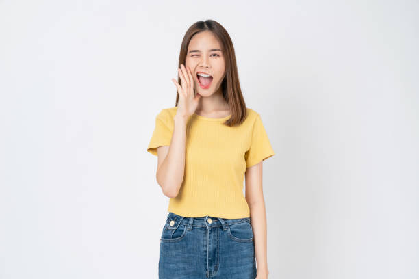 istock Young asian woman shouting and hands over mouth on white background studio. 2153754591