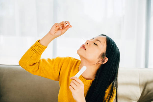 istock Woman at home uses a rapid antigen test kit inserting a swab into her nose 2153756819