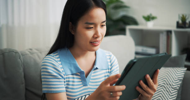 istock Young woman sits using a digital tablet on the sofa at home. 2153766256