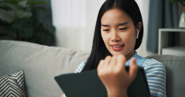 istock Young woman sits using a digital tablet on the sofa at home. 2153766326