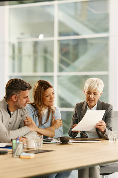 istock Senior advisor reading documents with a couple during a meeting in the office. 2153770024