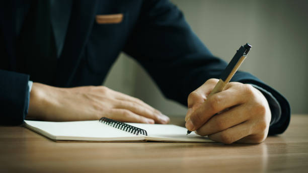 istock businessman working at work table,home office desk background, checklist writing planning investigate enthusiastic concept. Male hand taking notes on the notepad. 2153770388