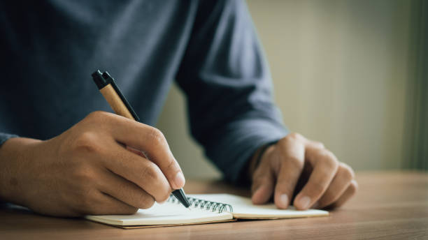 istock businessman working at work table,home office desk background, checklist writing planning investigate enthusiastic concept. Male hand taking notes on the notepad. 2153770431