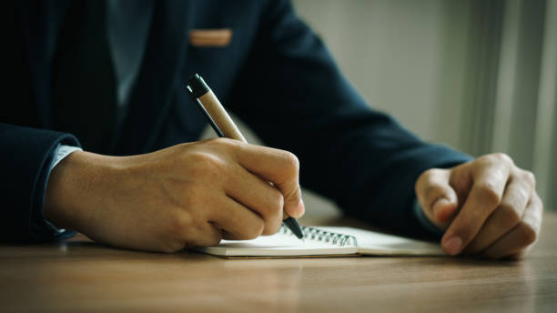 businessman working at work table,home office desk background, checklist writing planning investigate enthusiastic concept. Male hand taking notes on the notepad.