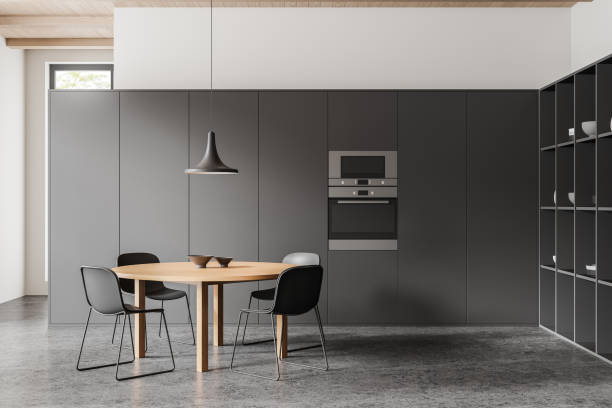 istock Modern kitchen interior with a wooden table, black chairs, built-in appliances, and a pendant lamp, on a concrete floor. 3D Rendering 2153773375