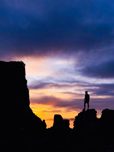 istock Silhouette of man standing on rocks looking towards the dramatic sky 2153775595