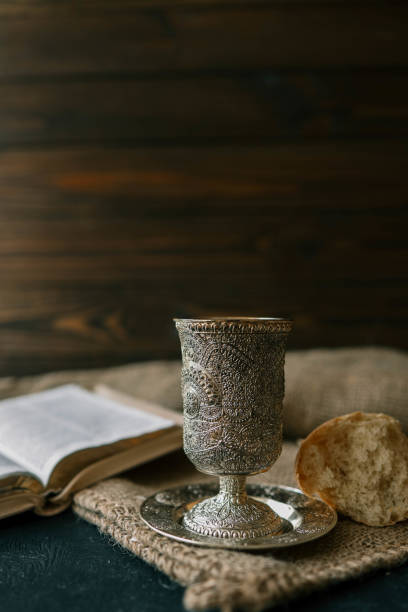 istock Cup with wine, bread and open Bible, Christian communion 2153775744