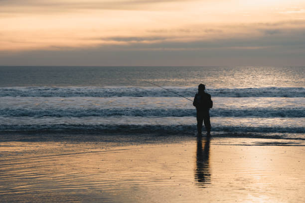 istock Fisherman standing in the ocean water during sunset 2153775894
