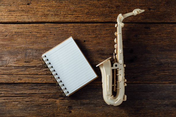 saxophone with paper note book wood on wooden background