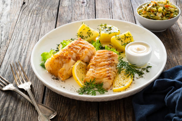 istock Fried codfish fillet and boiled potatoes served on wooden table 2153776065