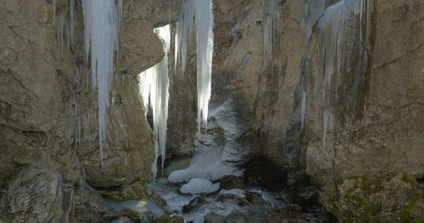 istock CLOSE UP Water dripping from icicles hanging on rocky wall above mountain stream 2153776180