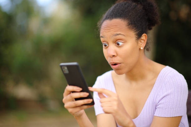 istock Amazed black woman checking cell phone outside 2153777010