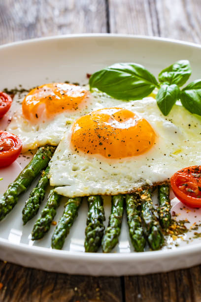 Sunny side up eggs with green asparagus on wooden table