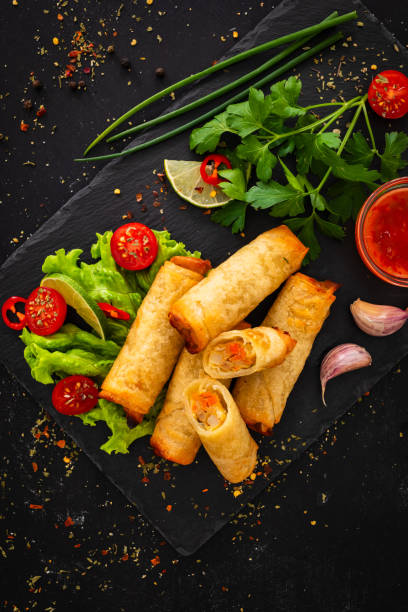 istock Spring rolls filled with meat and vegetables served with soy sauce on wooden table 2153780177