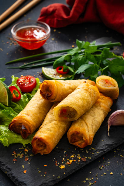istock Spring rolls filled with meat and vegetables served with soy sauce on wooden table 2153780198