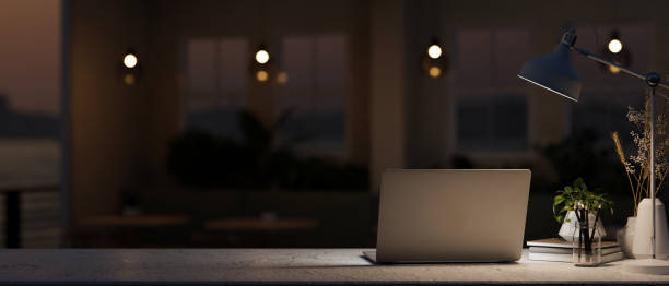 istock A table features a laptop computer and a dim light from a lamp in a dark coffee shop at night. 2153781054