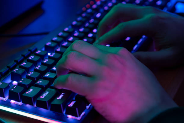 istock Close-up On Gamer's Hands on a keyboard, Actively Pushing Buttons, Playing MMO Games Online. Background is Lit with Neon Lights. 2153781113