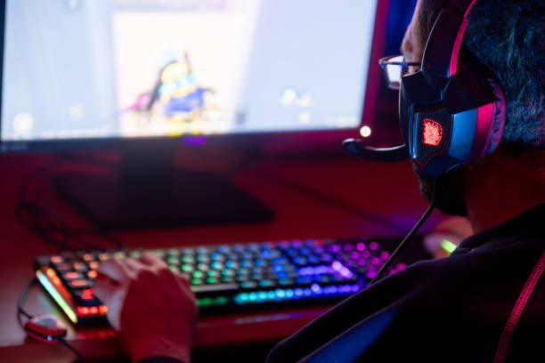 istock Gamer deeply engaged in a game, surrounded by colorful lights and high-tech equipment. 2153781611