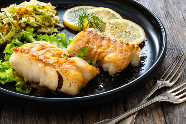 istock Fried codfish fillet and cabbage salad served on wooden table 2153781913