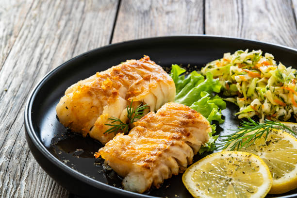 istock Fried codfish fillet and cabbage salad served on wooden table 2153781934
