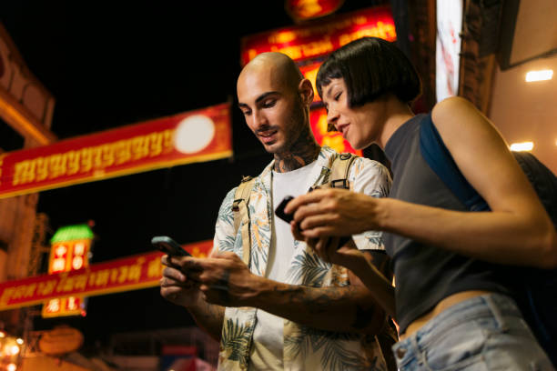 istock Couple using mobile phones while roaming in the city at night 2153782624