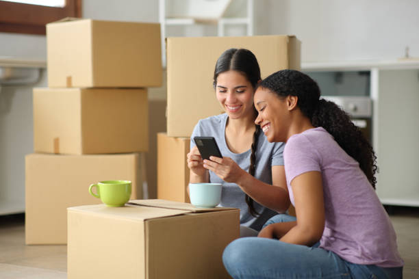 istock Black and white women checking phone moving house 2153786656