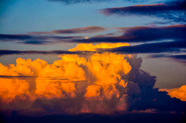 The sky is filled with clouds and the sun is setting. The clouds are orange and pink, creating a warm and peaceful atmosphere