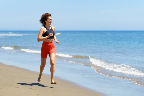 istock Happy young woman training on sandy beach and running 2153788083