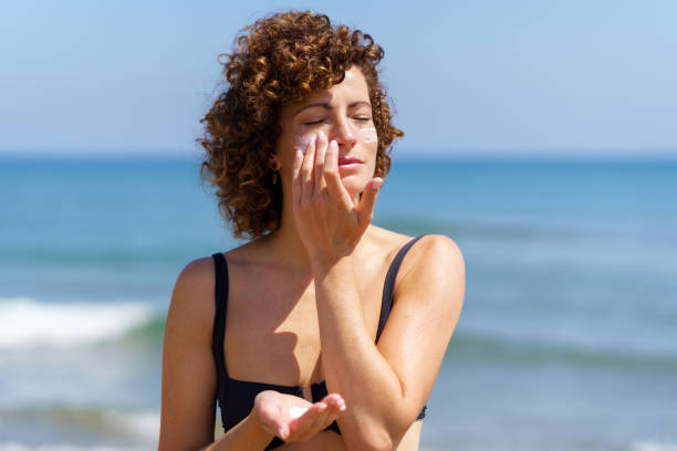 istock Young female smearing cream on face protecting from sunburn 2153788093