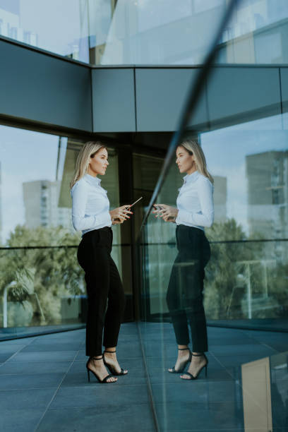 istock Confident businesswoman holding digital tablet while standing outside modern office building at noon 2153788262