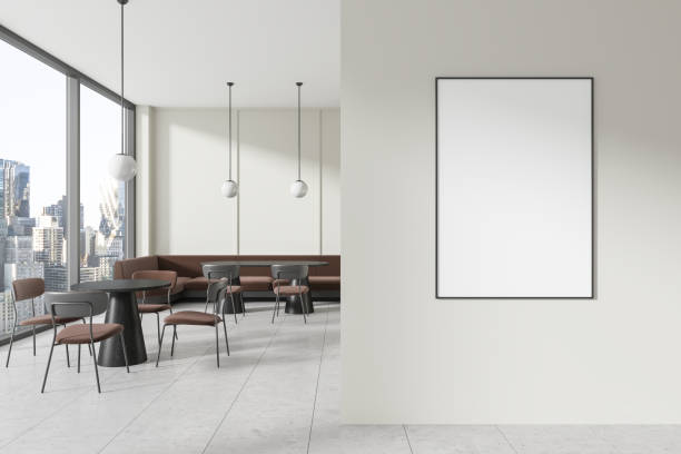istock A modern cafe interior with large windows overlooking a cityscape, featuring a blank poster on the wall for advertising, 3D Rendering. 2153789355