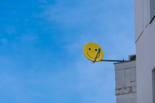 Germany, Berlin,  Schöneberg, April 11, 2024 -Satellite dish with yellow smily at building